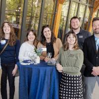 Group of staff from Institutional Advancement standing at outside table and posing for photo
